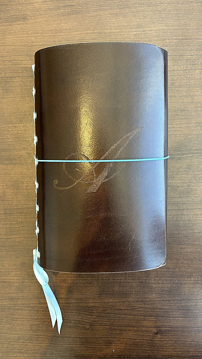 Forest green journal held in hand with M charm